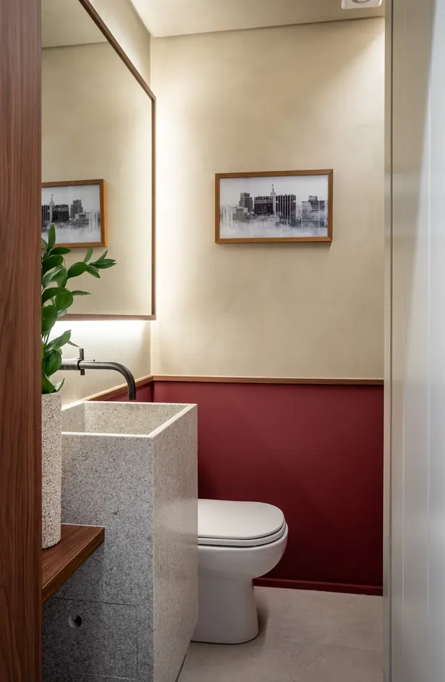Lavabo com meia-parede em bordô, cuba de apoio e metais escovados