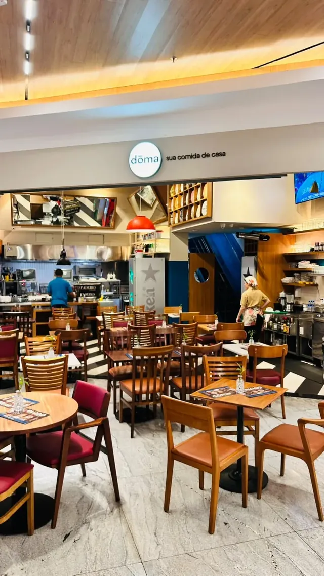 Salão de restaurante com mesas postas, luminárias pendentes e balcão ao fundo